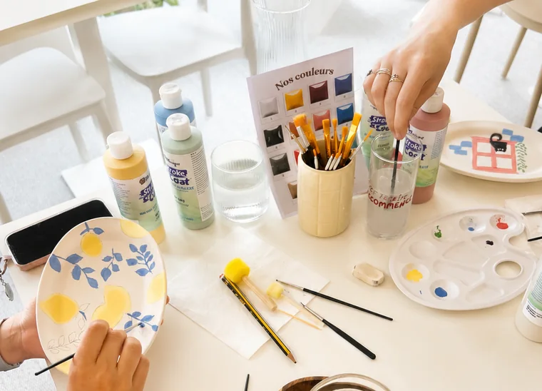 Séance de peinture sur céramique avec pinceaux, couleurs et assiettes décorées
